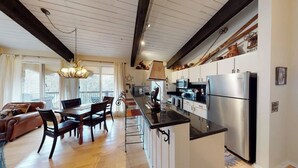 Eine geräumige Küche mit modernen Geräten, ein Essbereich mit Holzmöbeln und ein gemütlicher Wohnraum mit Kamin.