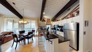 A spacious kitchen with modern appliances, a dining area with wooden furniture, and a cozy living room with a fireplace. - Lovely home near skiing with fireplace, balcony, & chic decor (Snowmass Village)