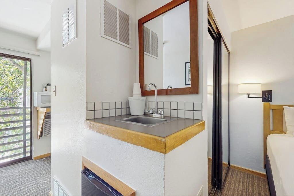 Un bany d'hotel amb un lavabo, mirall i zona de dutxa.