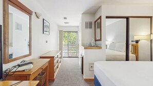 Una habitación de hotel con cama, escritorio, cómoda, espejo, ventana y puerta.