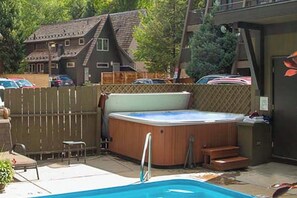Un patio trasero con piscina, jacuzzi y terraza de madera.