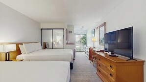 Een hotelkamer met twee bedden, een televisie, een bureau en een dressoir.