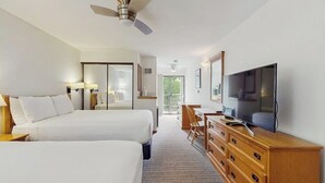 Ett hotellrum med två sängar, ett skrivbord, en tv och en takfläkt.