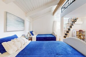 Een slaapkamer met twee bedden, een trap en een boekenkast.