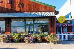 A wooden building with a green awning, large windows, and a yellow sign with 'Happy go smile' text. - Charming, two-story home with deck, grill, and ocean views (Cayucos)