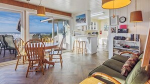 Un amplio salón con una mesa de comedor de madera, sillas, un sofá y una zona de cocina.