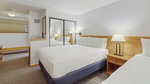 Ett hotellrum med en stor säng, sängbord, en spegel och en liten arbetsplats med ett skrivbord.