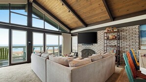 A large living room with a sectional sofa, a fireplace, a TV, and a view of the ocean. - Beachfront home with amazing ocean views, a two-level deck, and bikes (Oceano)