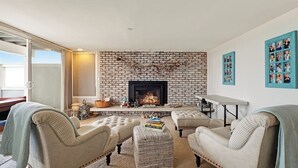 A living room with a brick fireplace, two armchairs, a sofa, and a coffee table. - Beachfront home with amazing ocean views, a two-level deck, and bikes (Oceano)