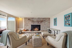 Ein Wohnzimmer mit Kamin aus Ziegelsteinen, zwei Sesseln, einer Couch und einem Couchtisch.