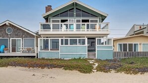 A two-story beach house with a balcony, large windows, and a wooden deck. - Beachfront home with amazing ocean views, a two-level deck, and bikes (Oceano)