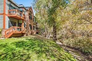 A multi-story building with a balcony, surrounded by trees and a grassy area. - Beautiful, waterfront condo w/ an updated interior and a gas fireplace (Basalt)
