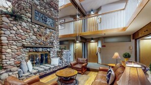 A spacious living area with a stone fireplace, leather sofas, and a wooden coffee table. - Main Street studio - pool & hot tub - walk to lifts, dog-friendly, second floor (Aspen)