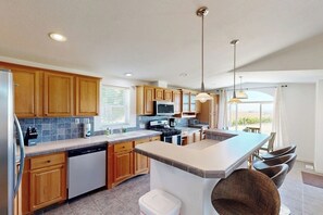 Una cocina moderna con armarios de madera, una isla central e iluminación colgante.