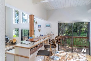 A modern kitchen with a wooden island, bar stools, and large windows.