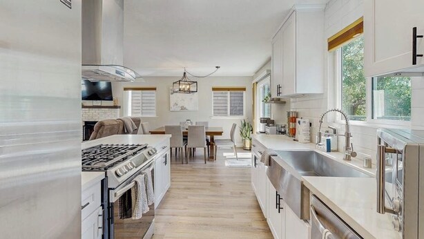 Een moderne keuken met een centraal eiland, een zithoek en een groot raam voor natuurlijk licht.