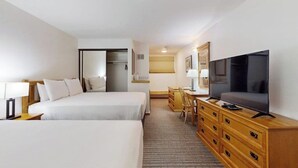 Een hotelkamer met twee bedden, een televisie, een bureau en een kledingkast.