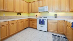 A kitchen with wooden cabinets, a white stove, and a microwave. - Dog-friendly home near beach with fireplace, grill, yard, & W/D (Grover Beach)