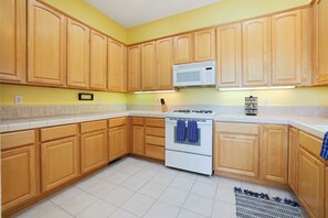 Una cocina con gabinetes de madera, una estufa blanca y un microondas.