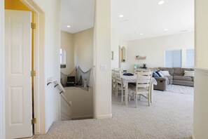 A spacious living area with a dining table, sofa, and a staircase leading to another level.