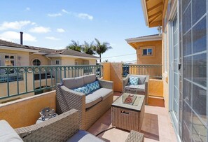 A balcony with wicker furniture, a glass door, and a view of neighboring buildings.