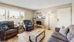 A living room with a fireplace, a sofa, a coffee table, and a wall with a 'Beach' sign. - Terrific home close to the beach, restaurants, parks, and activities w/free WiFi (Grover Beach)