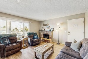 A living room with a fireplace, a sofa, a coffee table, and a wall with a 'Beach' sign. - Terrific home close to the beach, restaurants, parks, and activities w/free WiFi (Grover Beach)