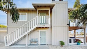 A two-story building with a white exterior, a balcony, and a staircase leading to the entrance. - Terrific home close to the beach, restaurants, parks, and activities w/free WiFi (Grover Beach)