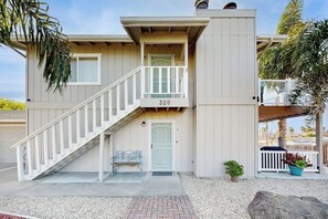 A two-story building with a white exterior, a balcony, and a staircase leading to the entrance. - Terrific home close to the beach, restaurants, parks, and activities w/free WiFi (Grover Beach)