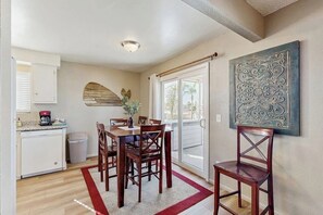 A dining area with a table and chairs, a kitchen with a dishwasher, and a sliding glass door leading to a balcony. - Terrific home close to the beach, restaurants, parks, and activities w/free WiFi (Grover Beach)