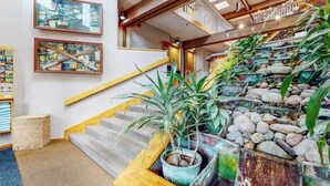 Un escalier avec une rampe en bois, des plantes en pot et un mur en pierre.