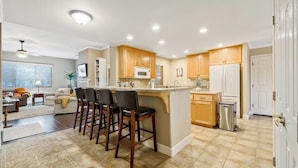 A modern kitchen with a central island, bar stools, and a refrigerator. - Comfortable home near beach with enclosed yard & patio, W/D, grill (Arroyo Grande)
