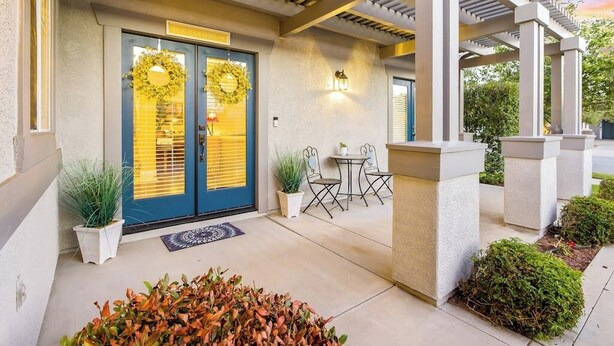 A building entrance with a covered patio, a blue door with wreaths, and outdoor seating. - Comfortable home near beach with enclosed yard & patio, W/D, grill (Arroyo Grande)