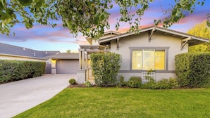 A modern two-story house with a well-maintained lawn, a garage, and a large window with blinds. - Comfortable home near beach with enclosed yard & patio, W/D, grill (Arroyo Grande)