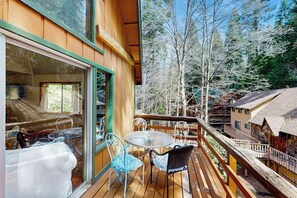 A wooden deck with a glass door leading to a room, a round table, and chairs.