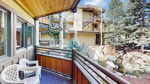 Ein Balkon mit Holzgeländer, einem kleinen Tisch und Stühlen.