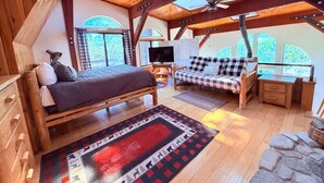 A cozy room with a bed, a sofa, a desk, and a TV.