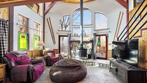 A cozy interior with a stone fireplace, wooden beams, and a large TV.