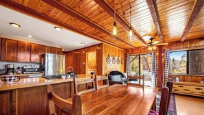 A wooden interior with a kitchen, dining area, and a large window.