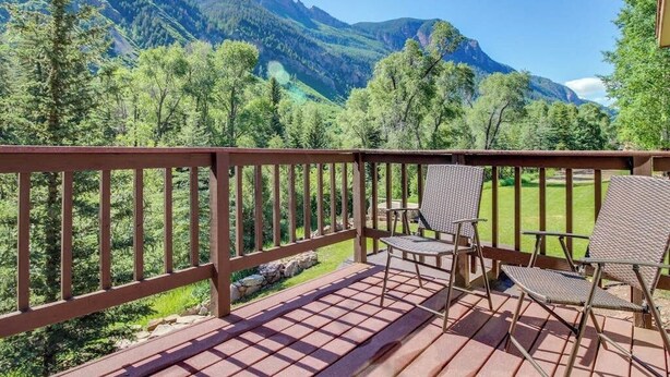 Une terrasse en bois offrant une vue sur les montagnes et les arbres.