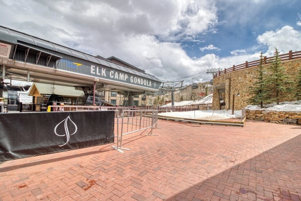 Un bâtiment portant l’inscription « ELK CAMP GONDOLA », doté d’une zone abritée et d’un mur en pierre surmonté d’une clôture.