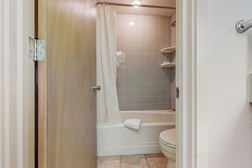 Un bagno con una vasca, un water e una tenda da doccia.