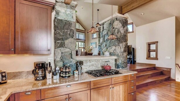 A kitchen with wooden cabinets, a stone accent wall, and a built-in stove.