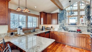 A kitchen with wooden cabinets, granite countertops, and pendant lighting.