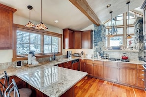 A kitchen with wooden cabinets, granite countertops, and pendant lighting. - Mountain retreat overlooking Breck Golf Course with hot tub, free WiFi, & W/D (Breckenridge)
