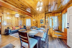Ein Holzblock-Interieur mit einem für vier Personen gedeckten Esstisch, einer Couch und einer Treppe.