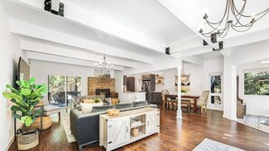 Amplia sala de estar con sofá, mesa de comedor y cocina al fondo.