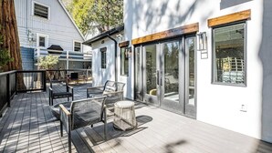 Una terraza moderna al aire libre con asientos, una chimenea y un ventanal de vidrio que da a un edificio.