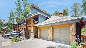 Una casa a due piani con garage, facciata in pietra e un'auto parcheggiata davanti.