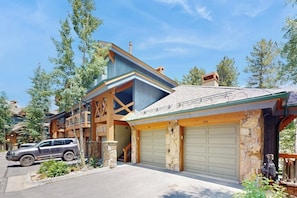 Ein zweistöckiges Haus mit Garage, Natursteinfassade und einem geparkten Auto davor.